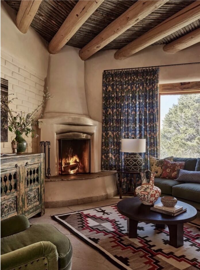 A fireplace built into a corner of a room with a large window beside it.