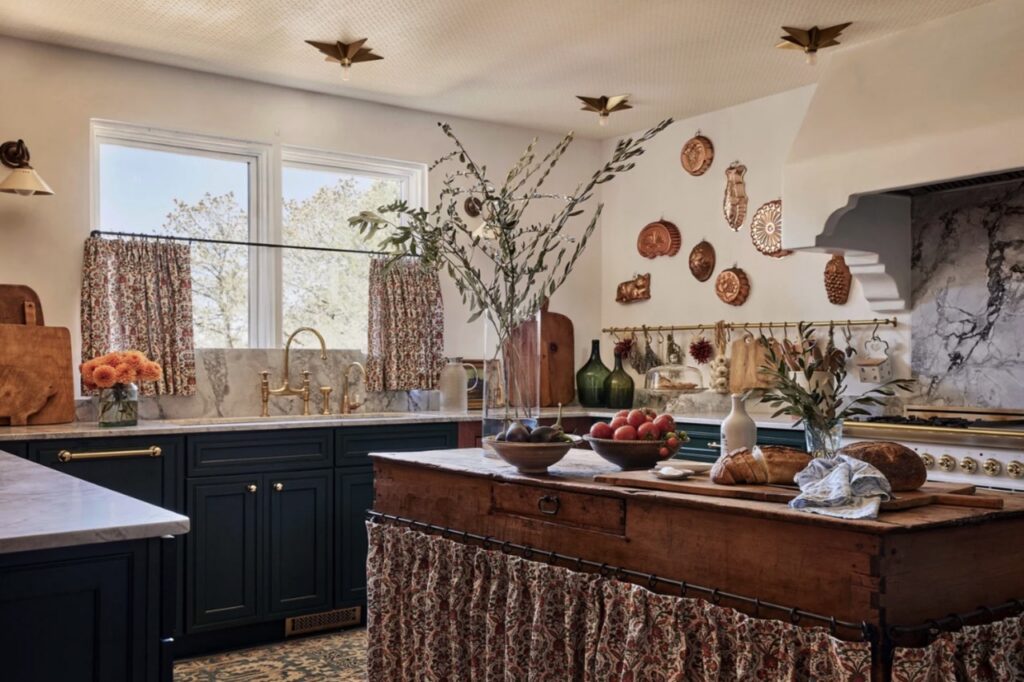 A kitchen interior with a brown wood counter top, white walls, and warm decor.