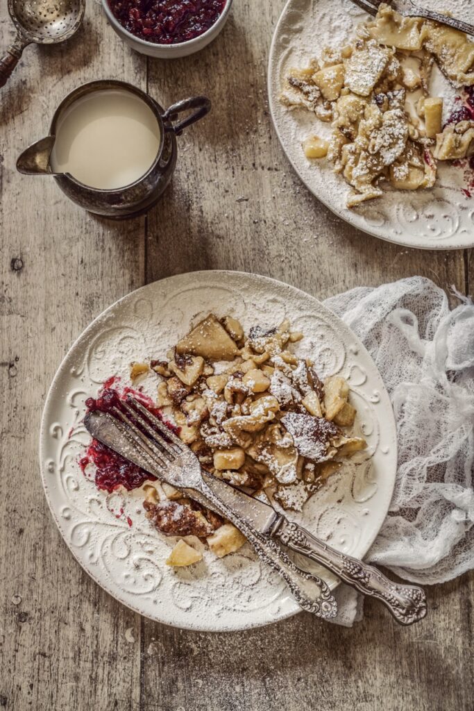 A plate of the Cortina dessert kaiserscharrn cut up into pieces with a knife and fork.