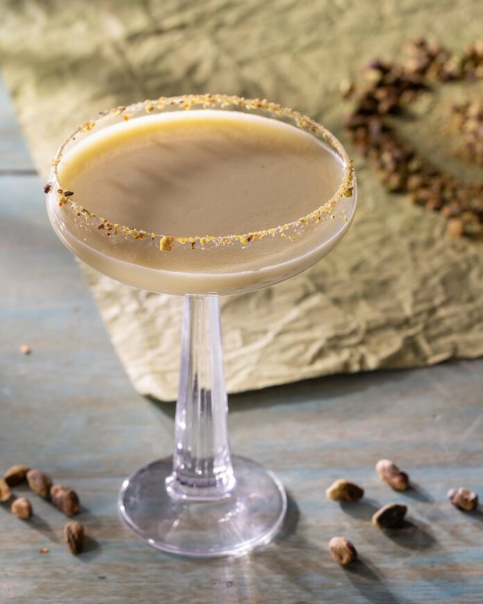 A tall coupe glass with a brown chocolate looking cocktail and crushed rim.