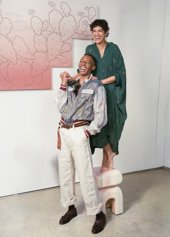 A woman in a dress stands on a stool behind a man in dress clothes.