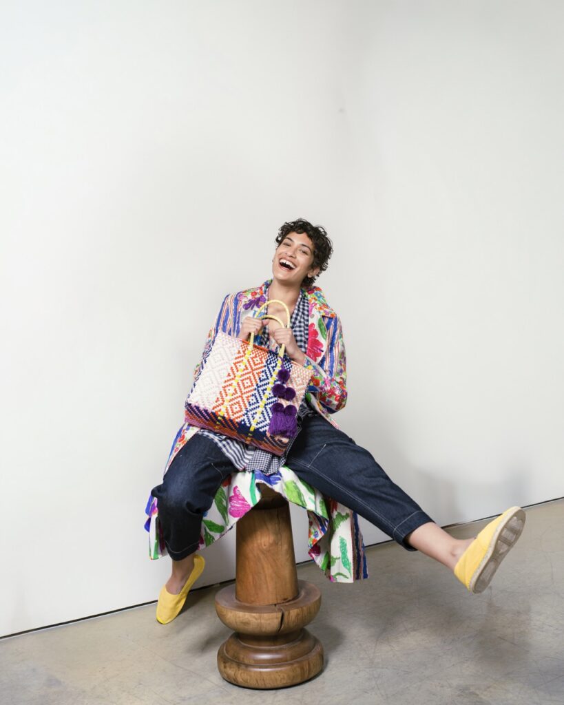 A woman kicks out her feet while sitting on a stool.