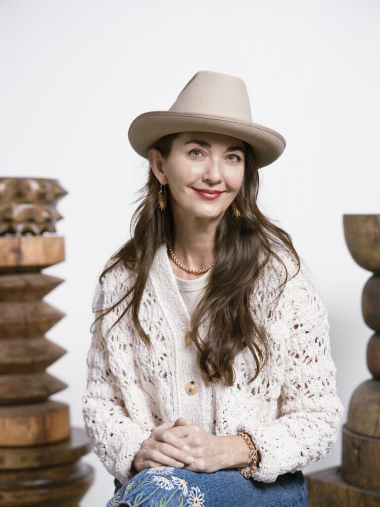 A woman sits in a white sweater with a beige hat on.