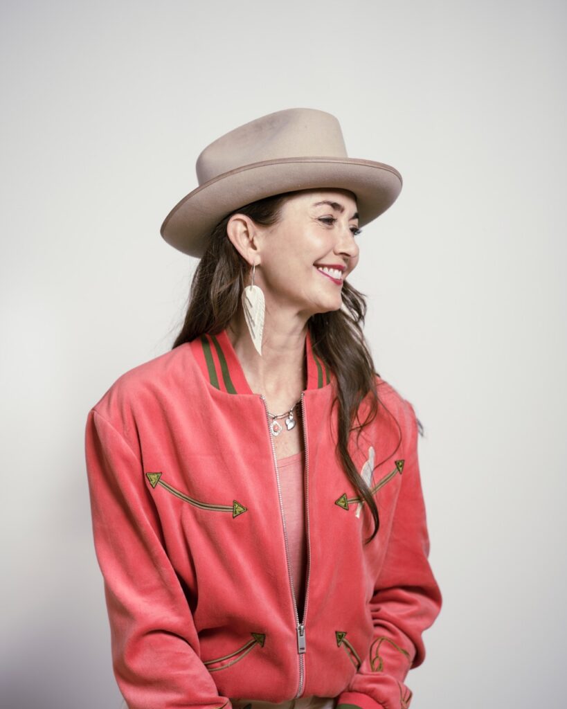 A woman in a pink blazer and beige hat. 
