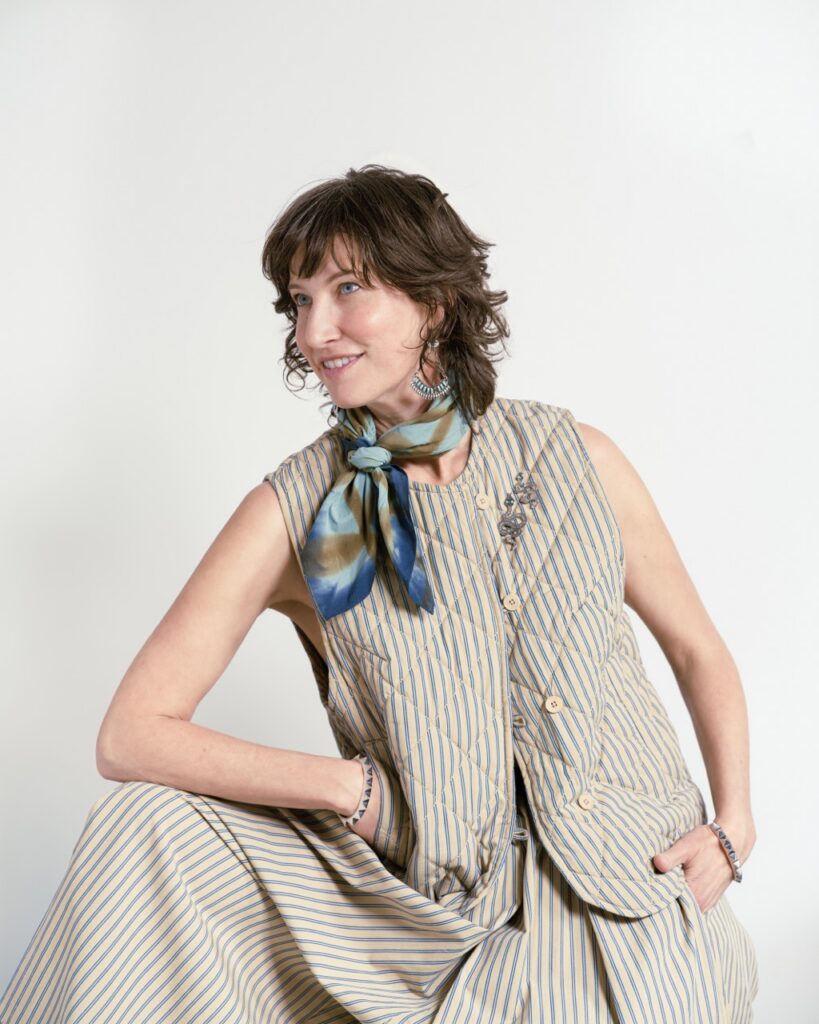 A woman in a grey vest and ascot.