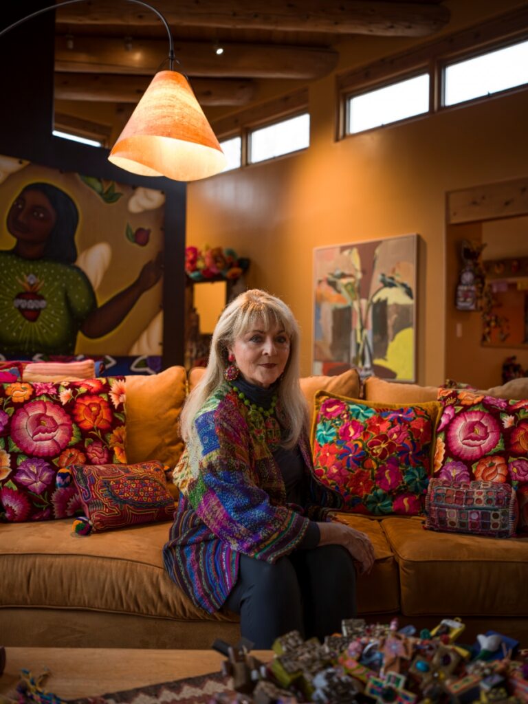 Folk art collector and jewelry designer Coreen Cordova in her vibrant Santa Fe home, surrounded by a colorful collection of Mexican alebrijes and statement jewelry.