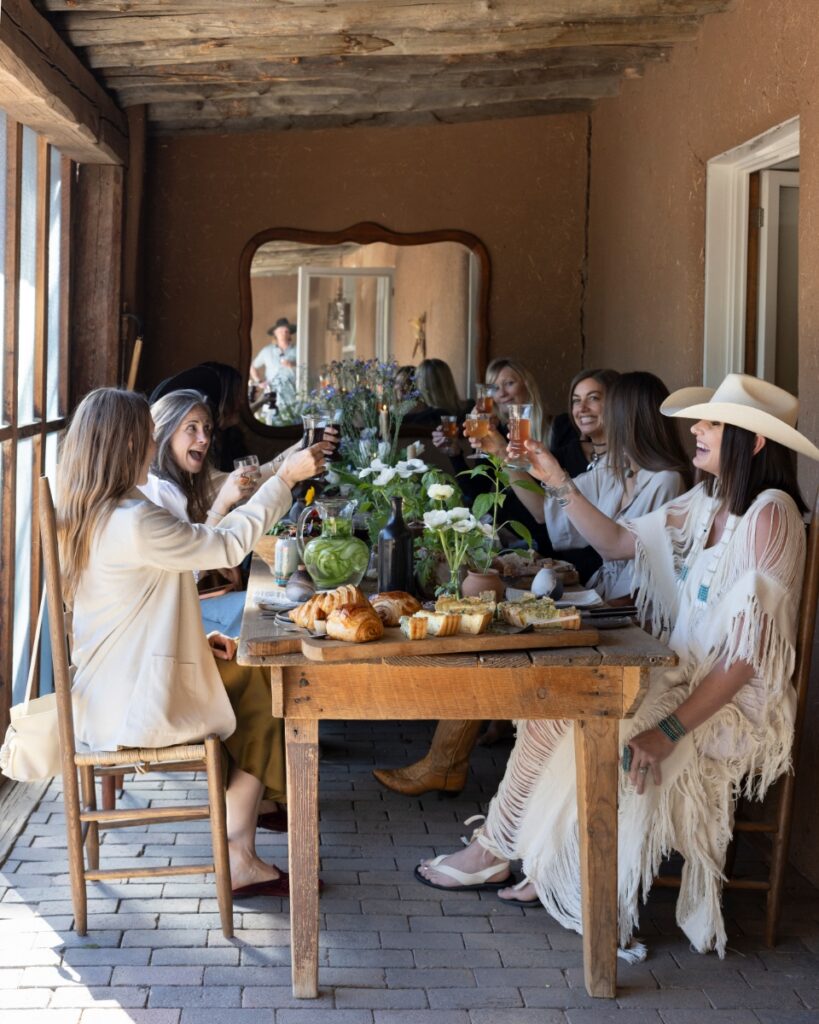 A group of friends enjoying a casual springtime brunch on a rustic porch at artist Katie Rodgers' historic adobe home in Santa Fe.