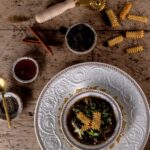 A bowl full of lamb and lettuce stew with strips of fried matzah around it.