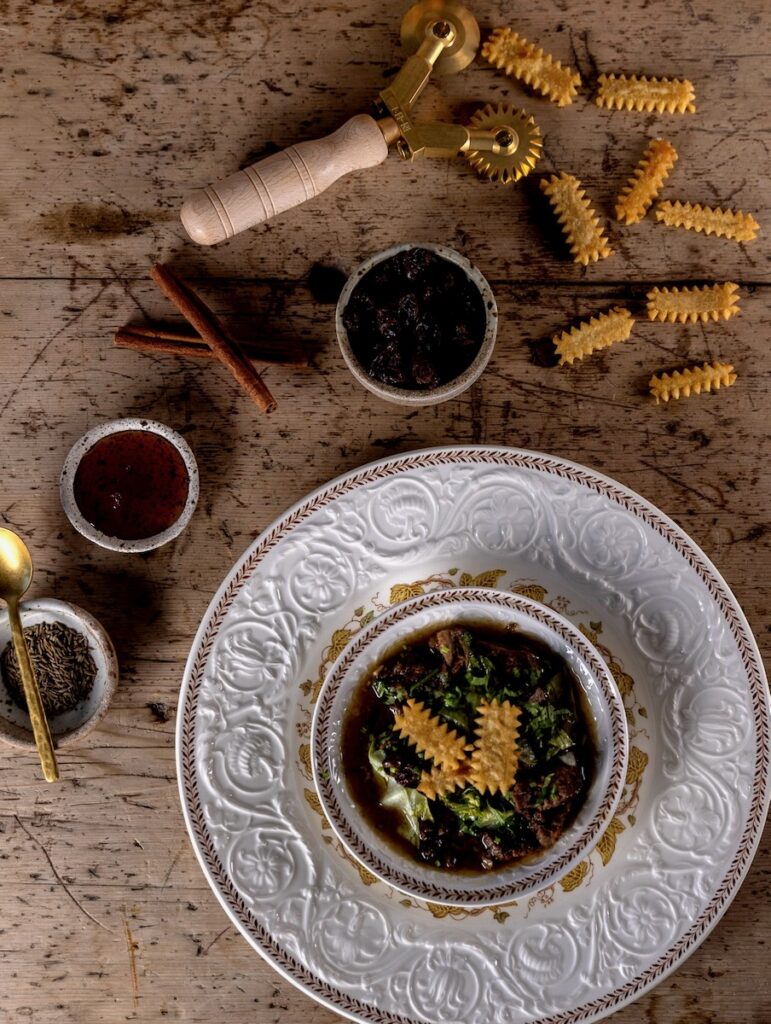 A bowl full of lamb and lettuce stew with strips of fried matzah around it.