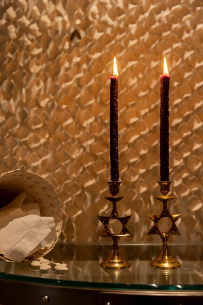 Two tall purple candles burning in brass Star of David candlesticks, a traditional ritual element of a Passover Seder hosted in Santa Fe.