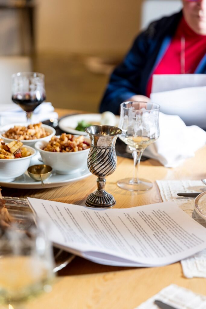A silver Kiddush cup and a printed Haggadah on a wooden dining table during a modern Passover Seder in Santa Fe.