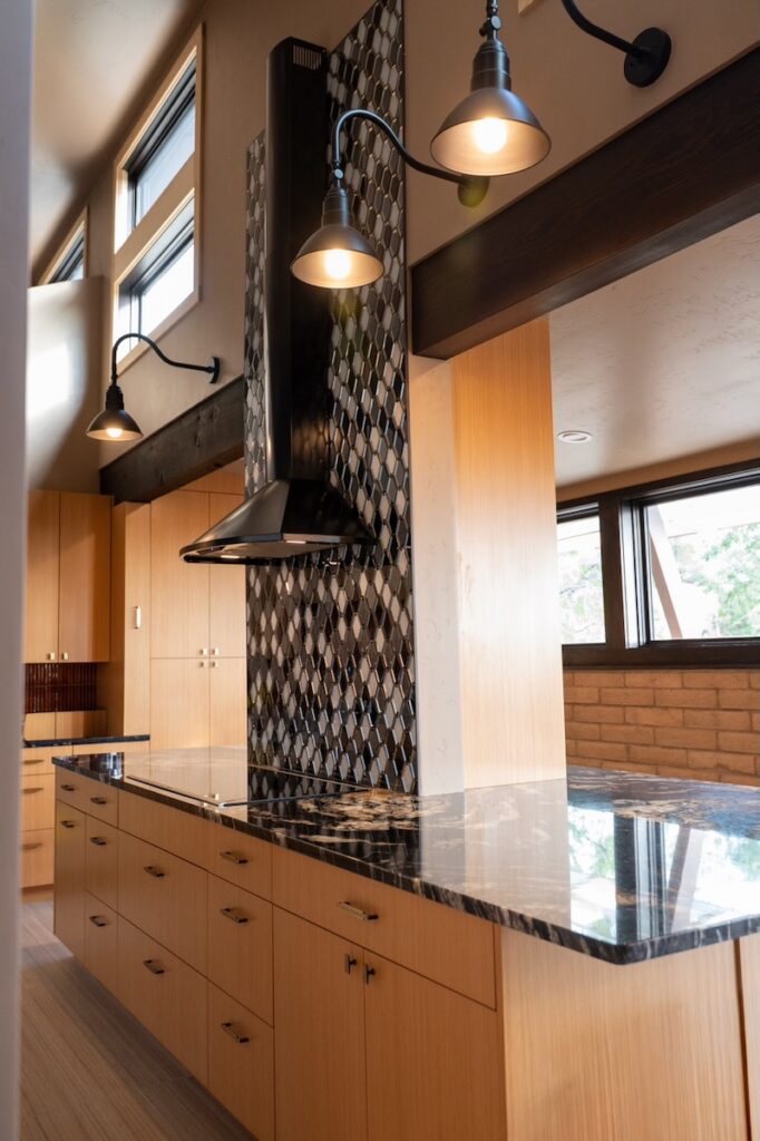 A tall tile column in dark colors behind a fight fixture all above a counter top.