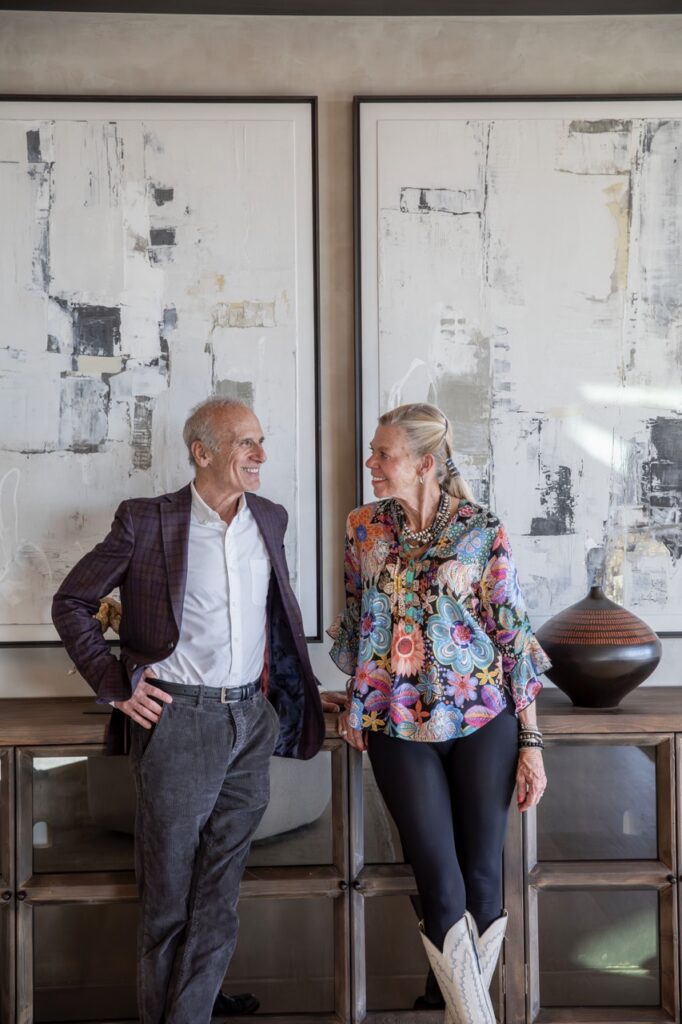 A man and a woman look at each other standing in front of two large framed pieces of art.