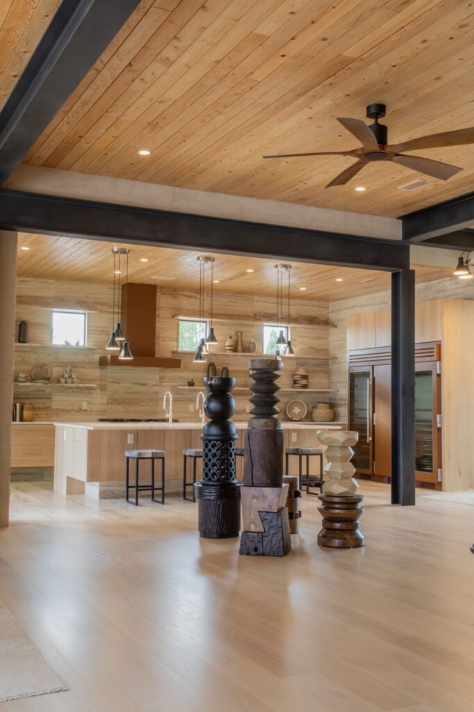 A large wood room area with three large sculptures in the center of the room.