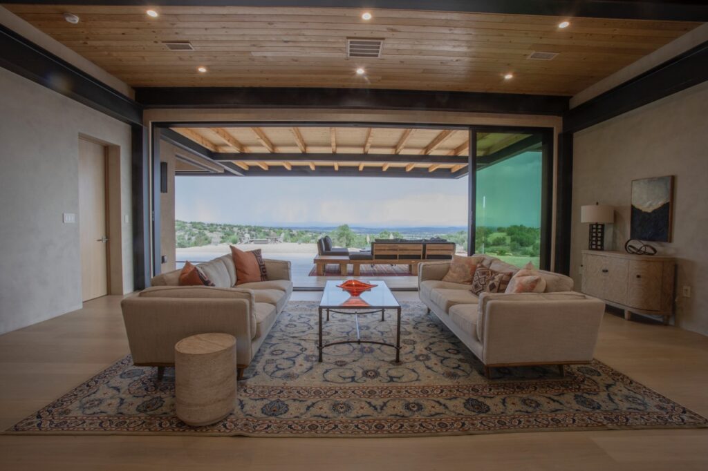A living room with an open window all across the wall and two couches facing each other.