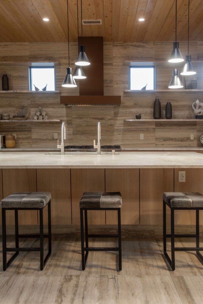 A sink and long whtie counter with stools sitting in front of it.