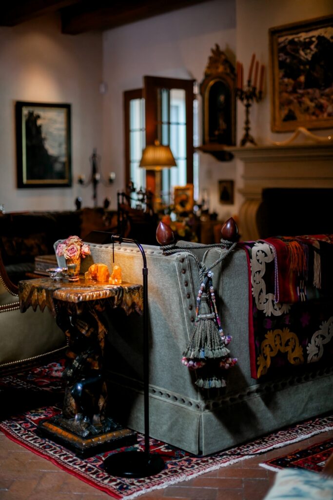 A global-inspired living room featuring an antique velvet sofa draped with an Uzbek suzani textile and decorative tassels, part of Suzanne Sugg's private collection.