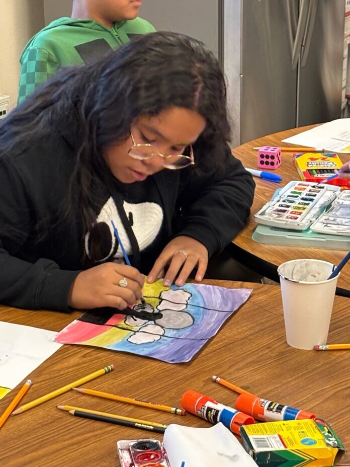 Gerards House TABLE Magazine 2 A girl colors a paper on a table.