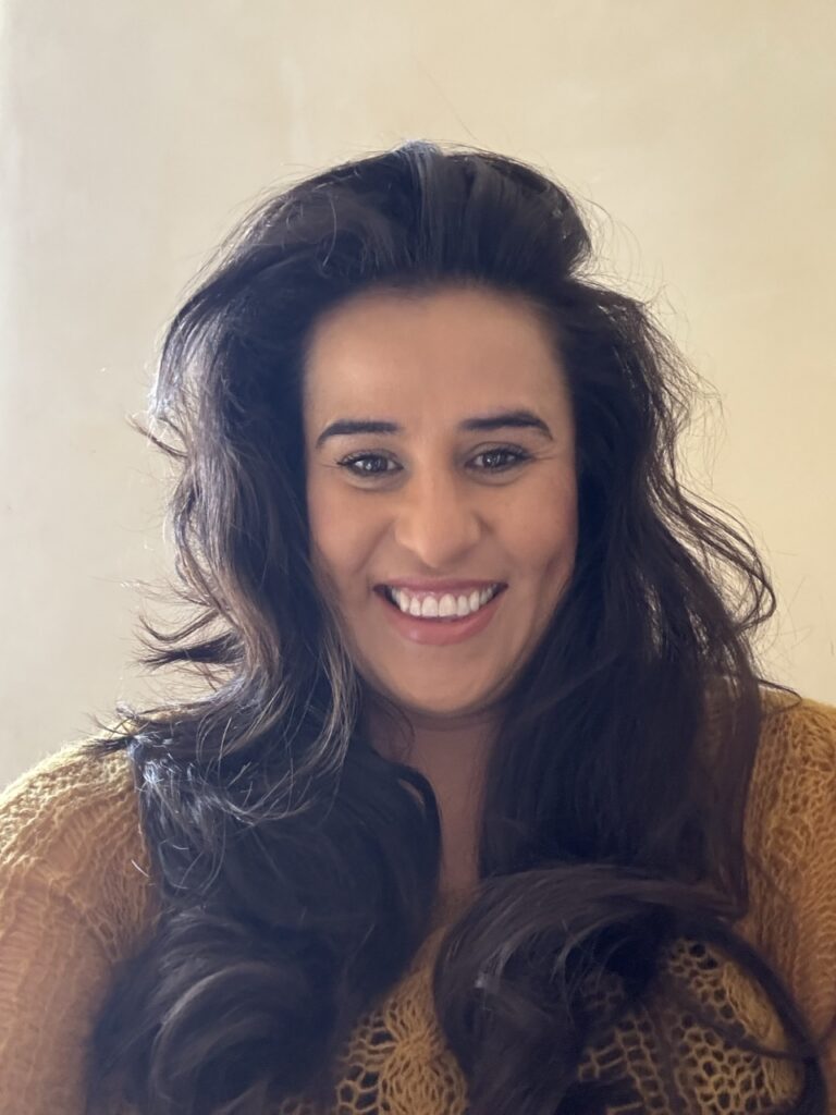 A woman with brown hair in a ochre sweater.