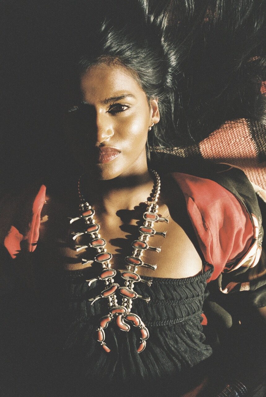 A woman in native jewelry laying back on a surface.