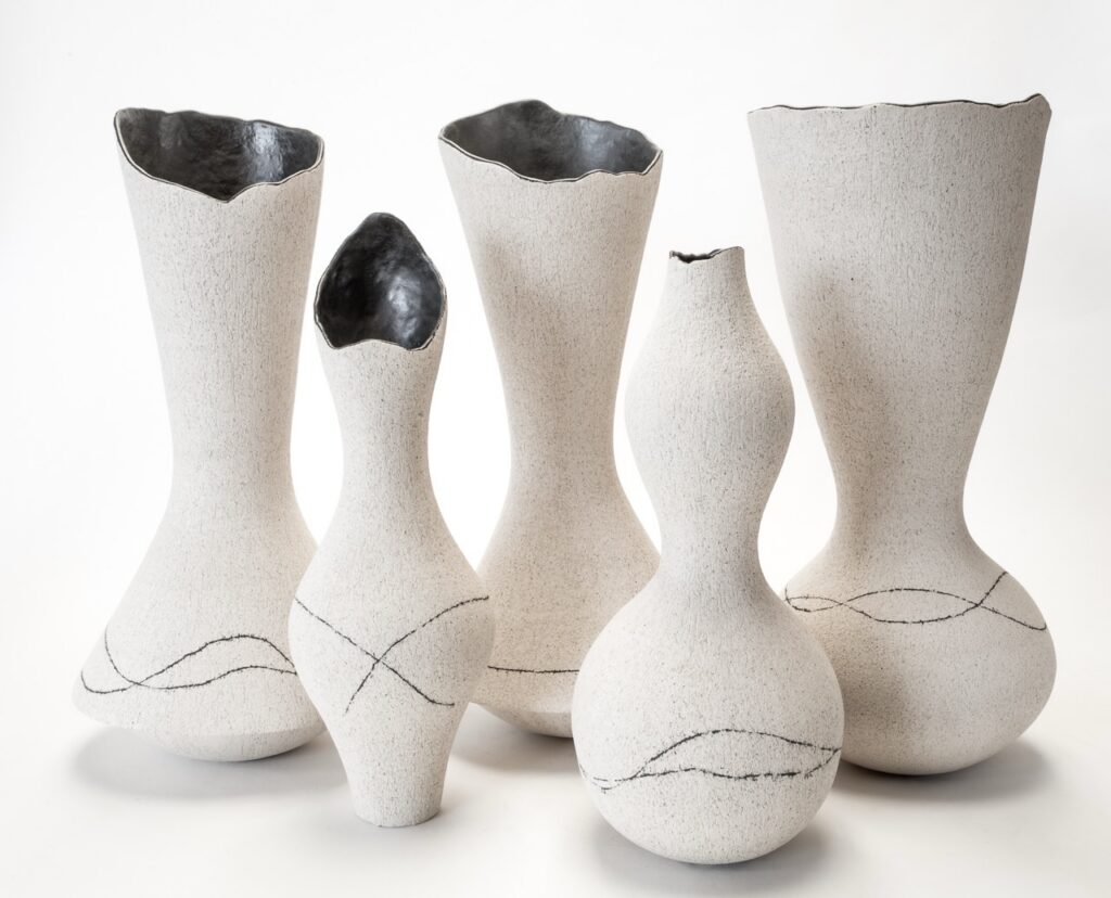 Five white vases in unique shapes with gray lines around the bottom.
