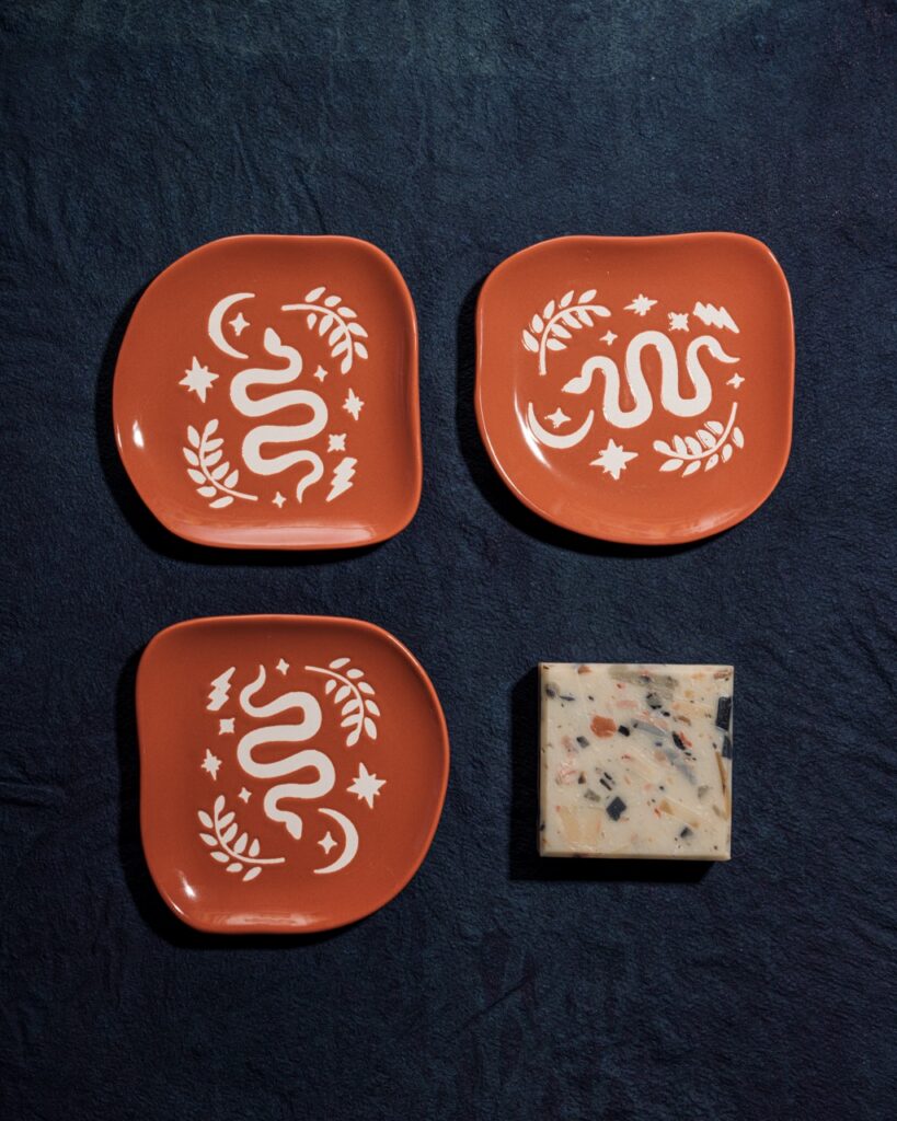 Three orange plates and a tile on a blue background.
