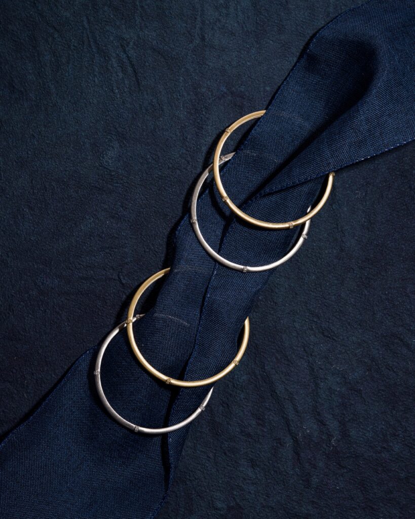 Two gold and two silver bracelets on blue fabric.