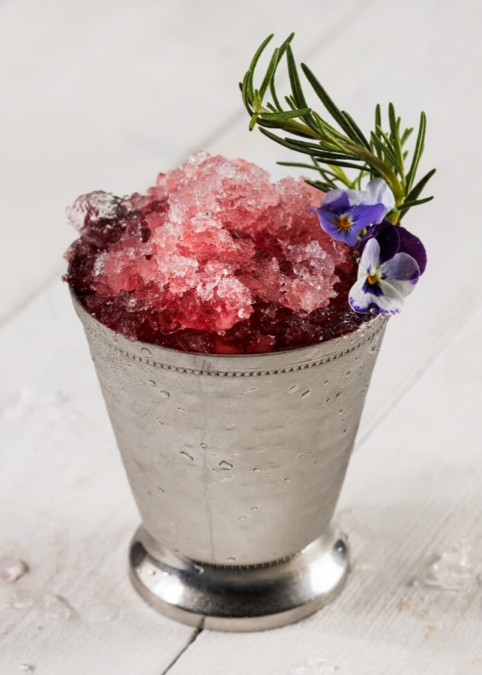 Pomegranate Mint Julep TABLE Magazine A pomegranate mint julep in a silver tin julep cup with crushed ice and a sprig of rosemary.