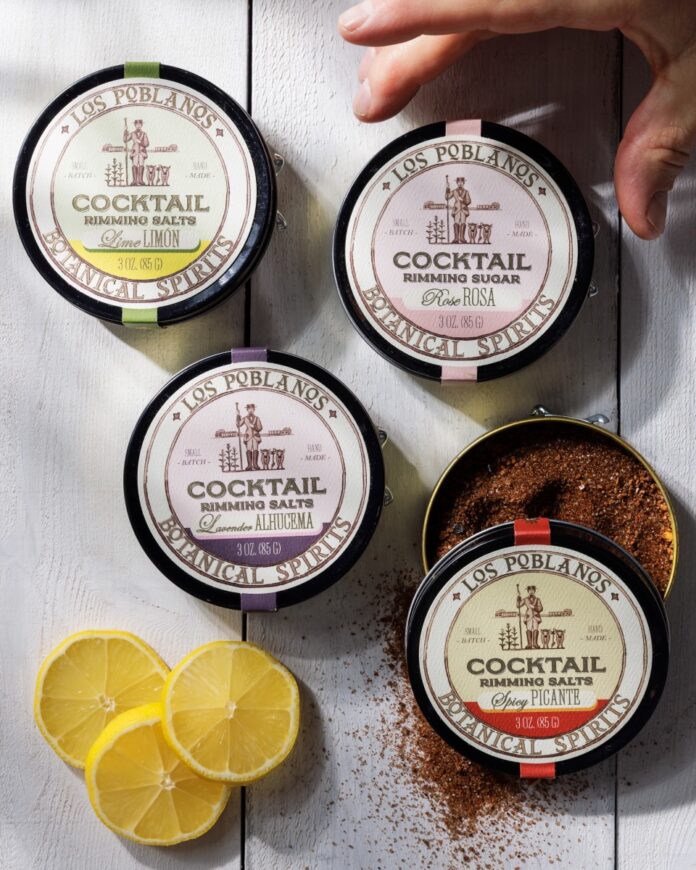 Los Poblanos Cocktail Rimming Salts TABLE Magazine Four different small containers of cocktail rimming salts from Los Poblanos sit on a white picnic table.