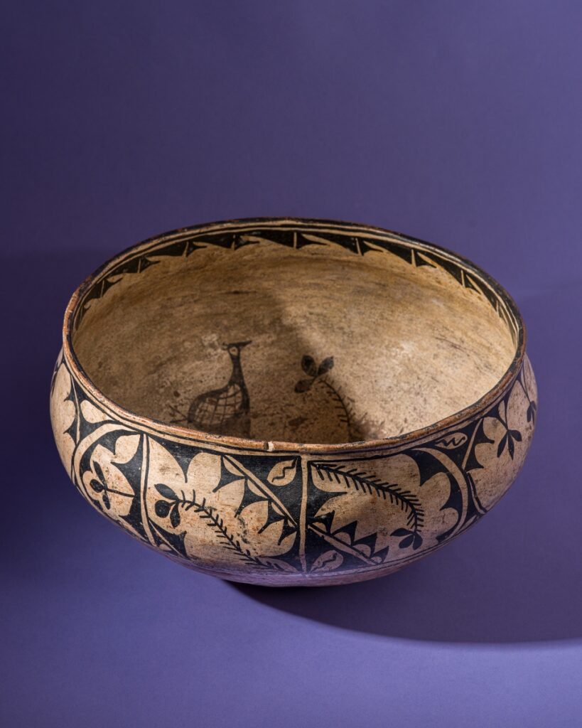A large historic Cochiti Pueblo pottery bowl from circa 1890, featuring traditional cream-colored clay with black painted bird and floral motifs around the exterior.