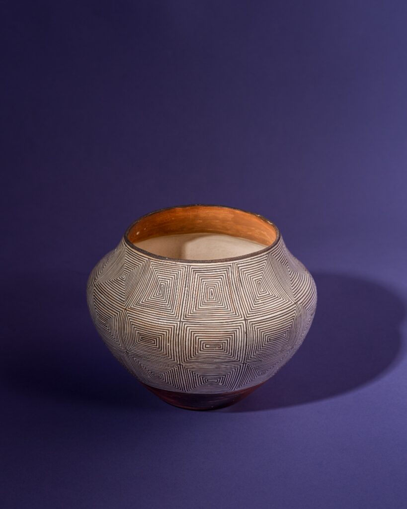 A traditional black-on-white Acoma Pueblo water jar created by Lucy Martin Lewis in 1947, featuring high-contrast geometric patterns and fine-line hatching in clay and paint.
