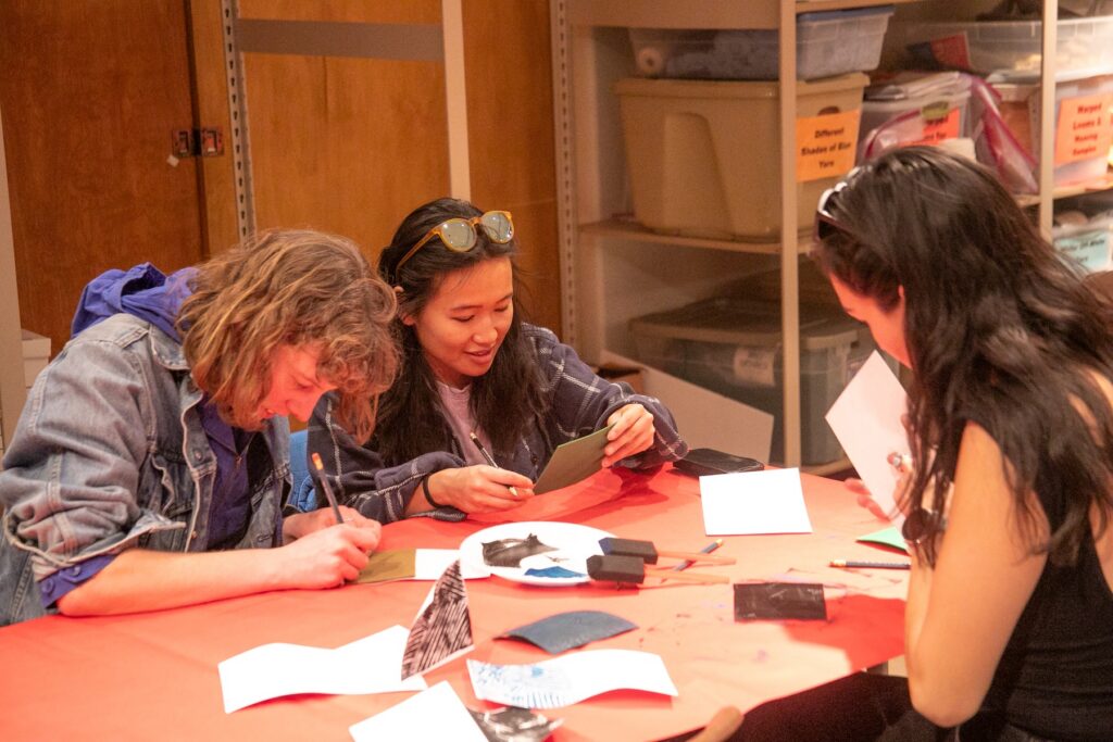 A group of three people sitting around a table working on an art project with paint at The Museum of Indian Arts and Culture in New Mexico.