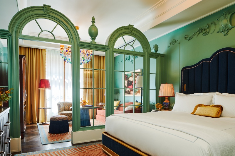 A Mansion Junior Suite at The Fifth Avenue Hotel showcasing bohemian romanticism with a velvet canopy bed, colorful patterns, and eclectic decor.