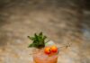 Camp Cooler: A Strawberry and Cherry Tomato Cocktail A short glass with a reddish tint and mint in the cocktail with cherry tomatoes and strawberries.