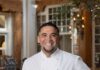 Chef Marc Quiñones Joins James Beard Foundation’s TasteTwenty Class Chef Marc Quinones in a white chefs jacket with his hand on the back of a wooden chair.