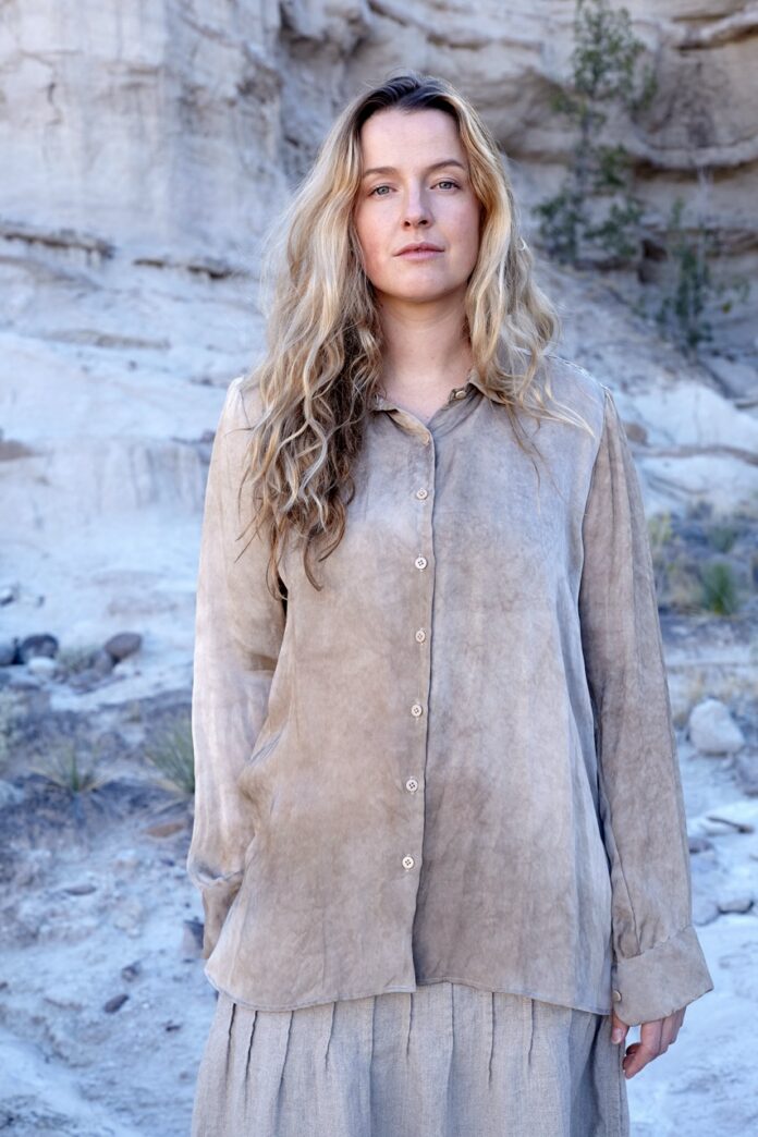 A woman in a long grey wash button shirt.