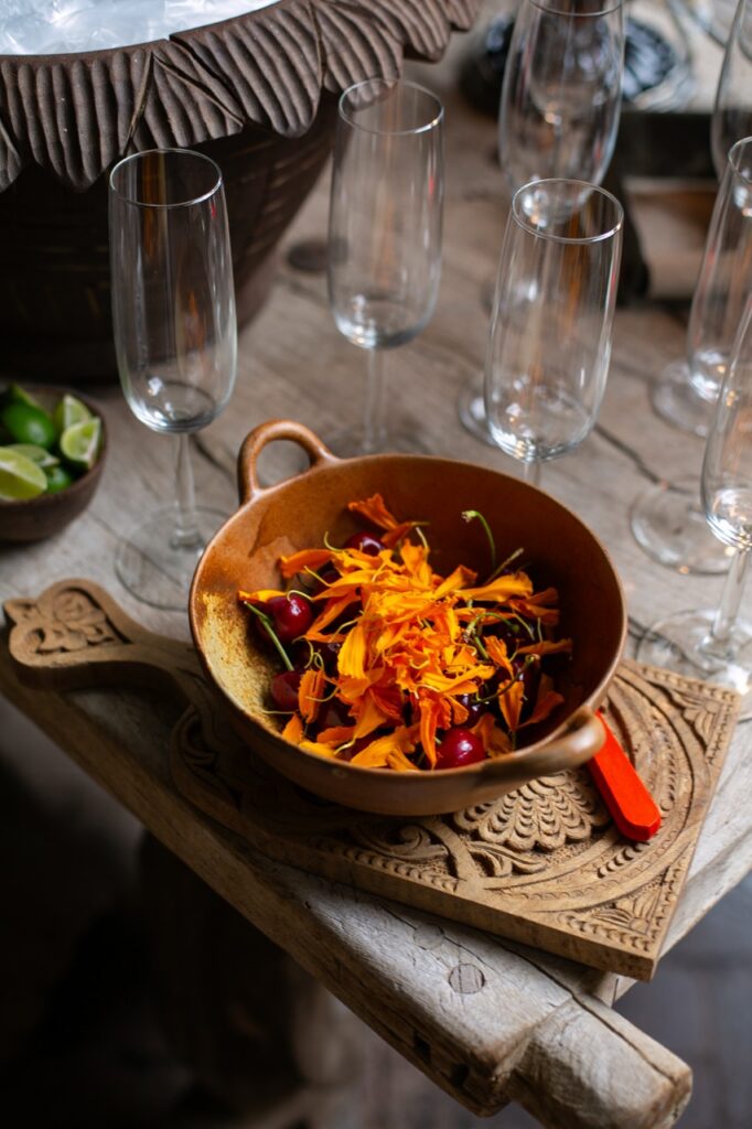 A brown bowl full of pasta on a brown table surrounded by empty champagne glasses.