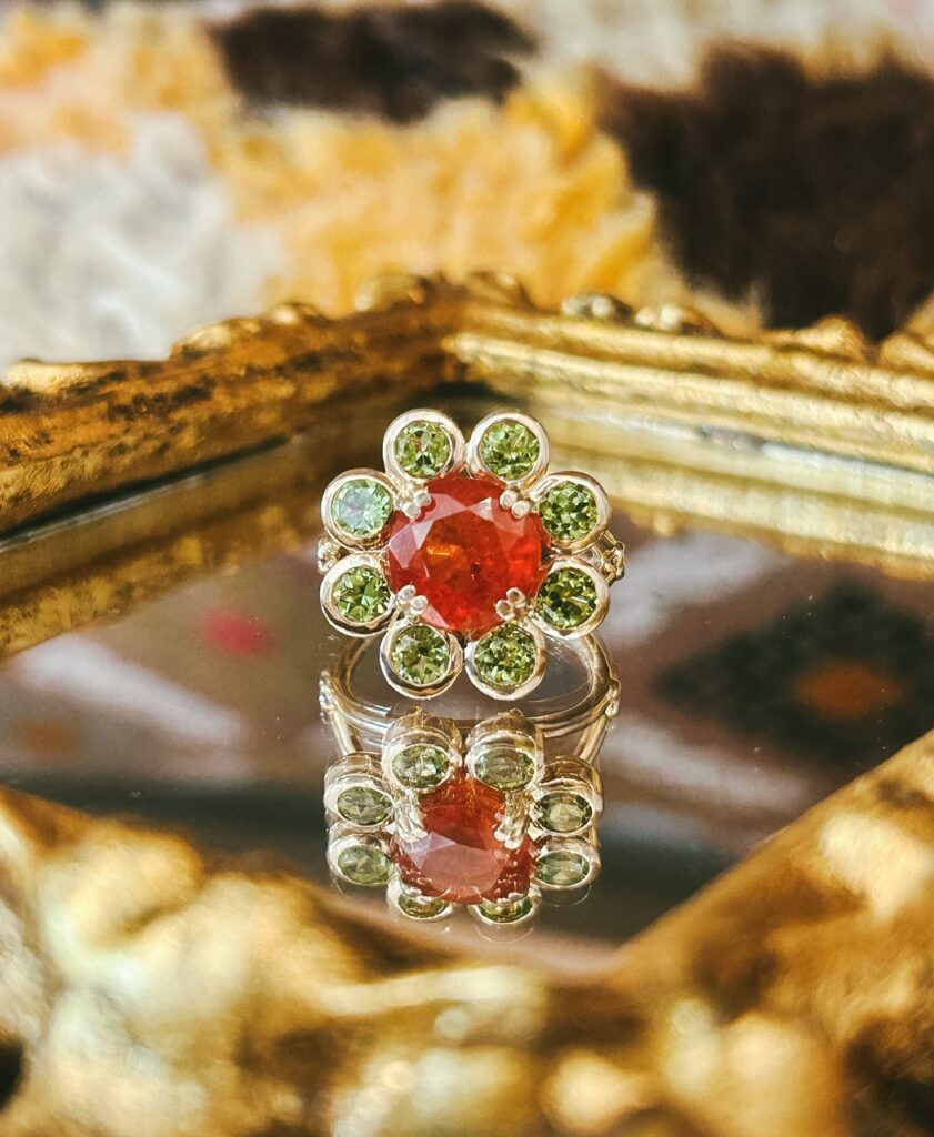 A ring that looks like a flower with green petals and an orange center.