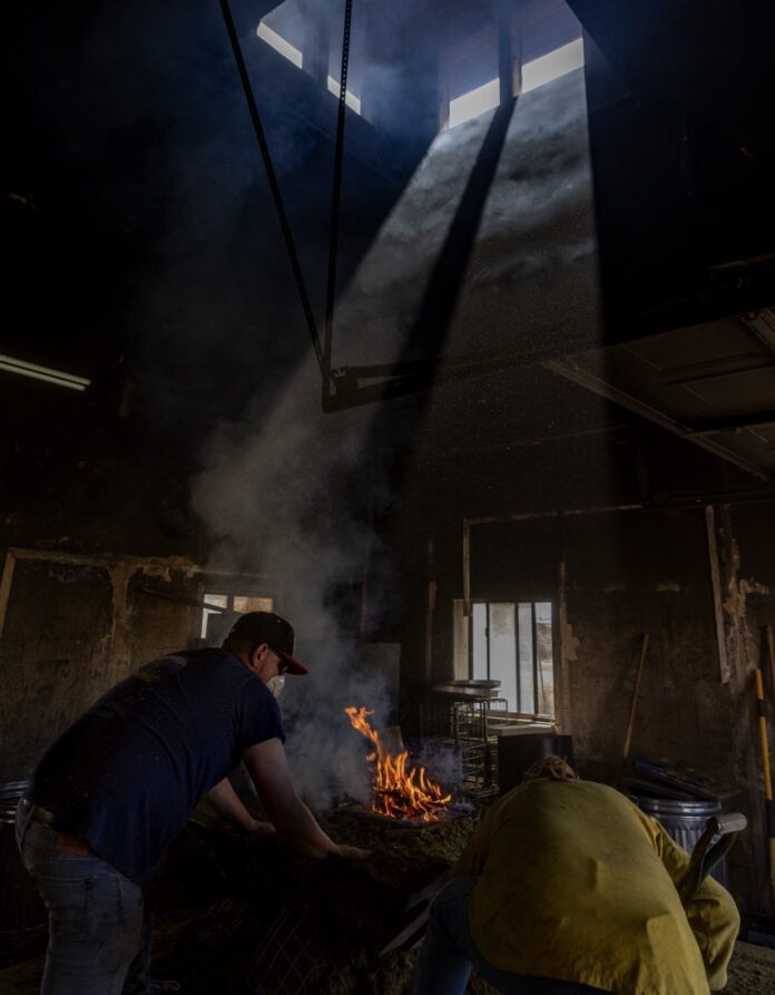 Two artists work on a ceramics project over a fire.