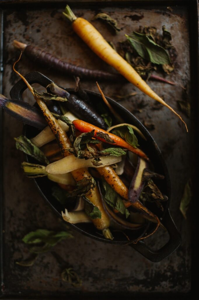 Various stringy carrots sit on a plate and stone.