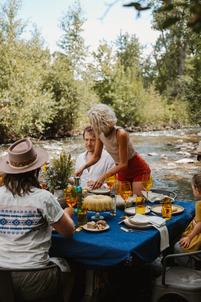 A woman places a plate down at a blue dining table in the river.
