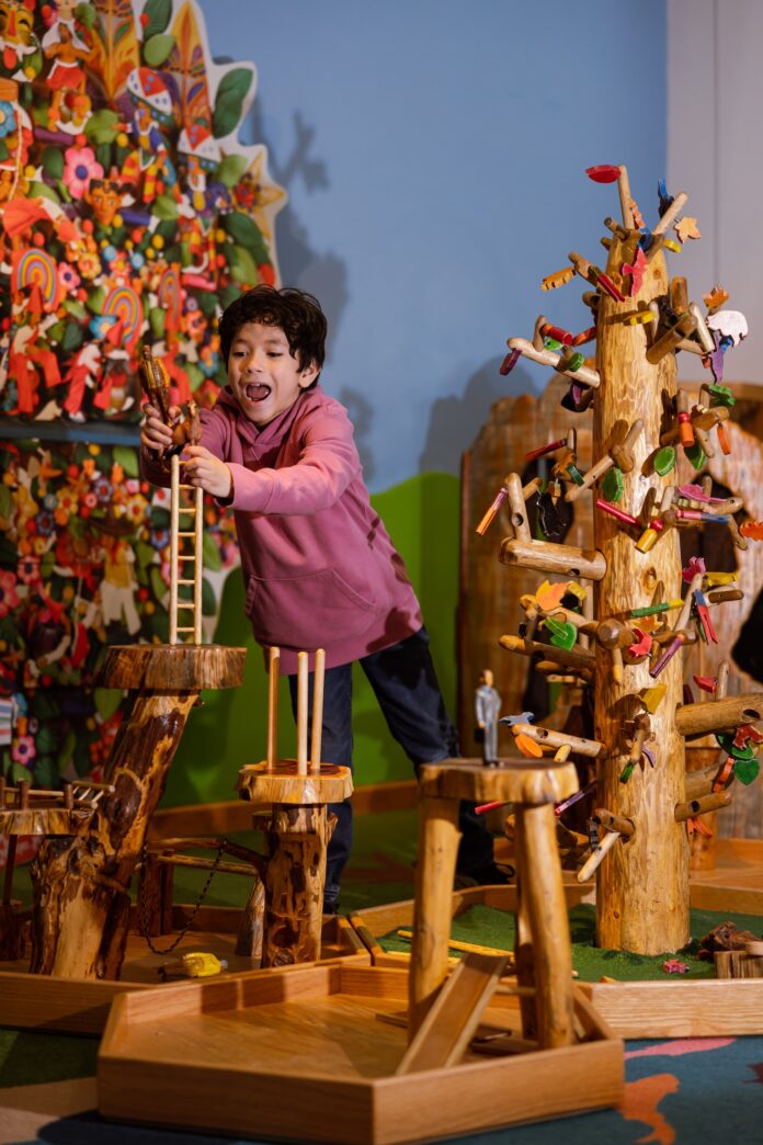 A child playing with wooden figurines on on wooden structure at the Santa Fe Museum of International Folk Art