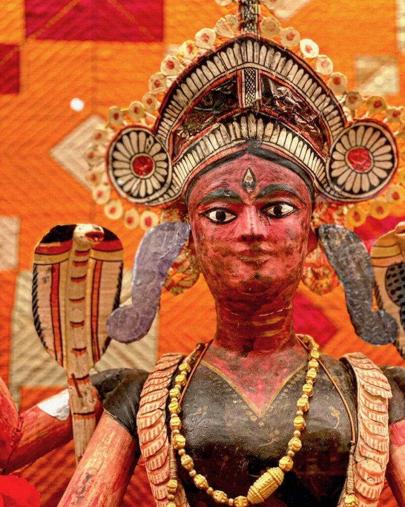 A folk art statue with an orange face and a large crown over top.