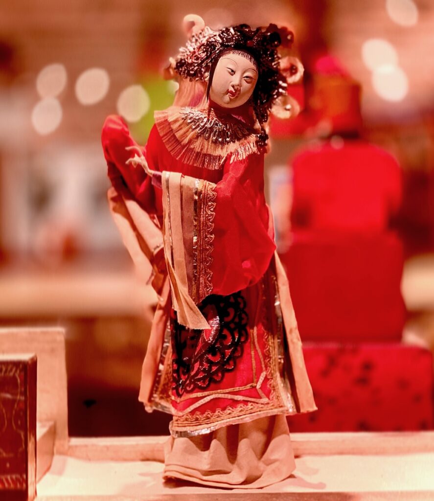A folk art statue of a woman in ceremonial red clothing.