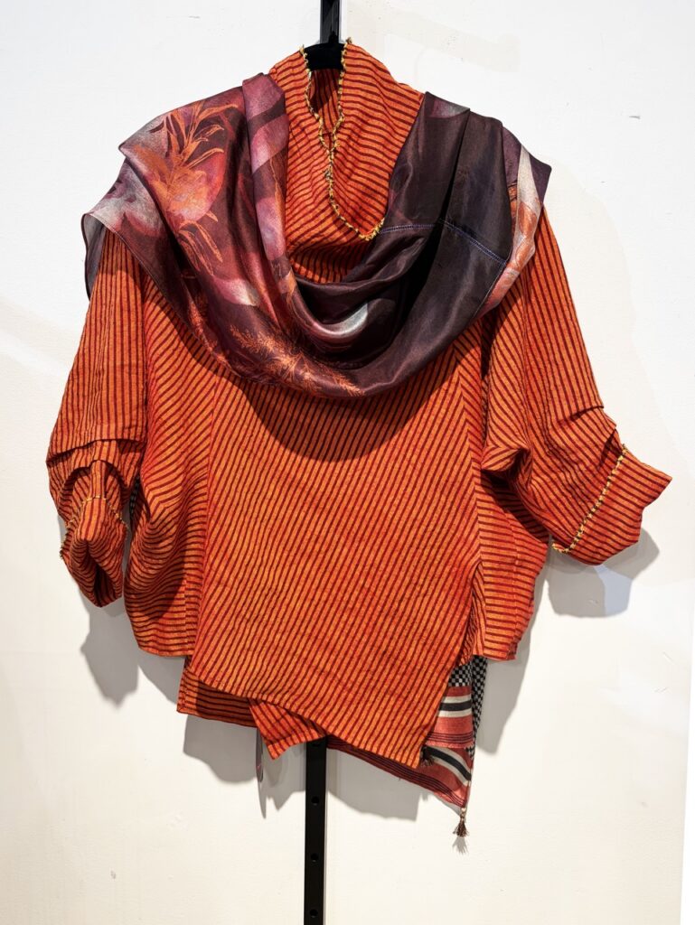 An orange shirt with a long flowing scarf life center.