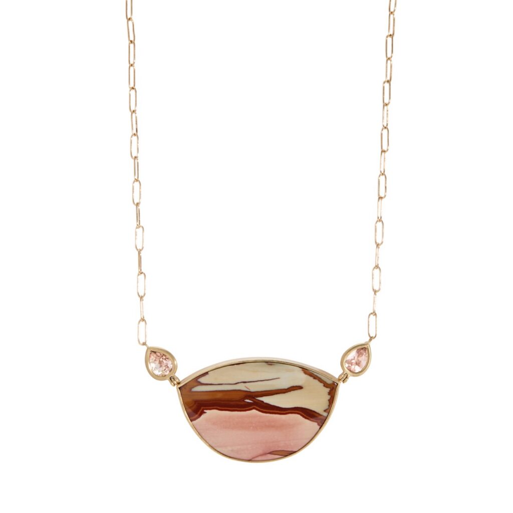 A gold chain necklace with a desert sand and pink pendant.