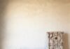 Santa Fe Summer Shopping: Artisan Furniture, Home Décor & Designer Jewelry A wood bench sits against a beige wall with pillows on it and a cabinet to the right.