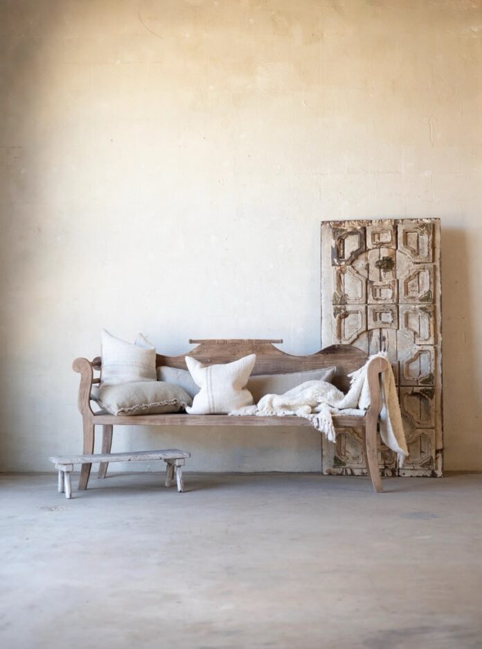 Santa Fe Summer Shopping: Artisan Furniture, Home Décor & Designer Jewelry A wood bench sits against a beige wall with pillows on it and a cabinet to the right.