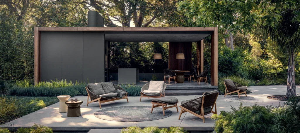The outside of a black one level modern home with patio furniture outside. 