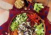 Asian Crunch Salad A bowl full of a salad with colorful crunchy vegetables in an Asian salad beside small bowls of veggies and a bowl of dressing.